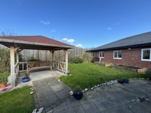 Grass and a wide path with a pergola and bench