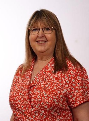 Picture of Clr Pauline Beall. Female, shoulder length blonde hair with glasses, wearing a red dress