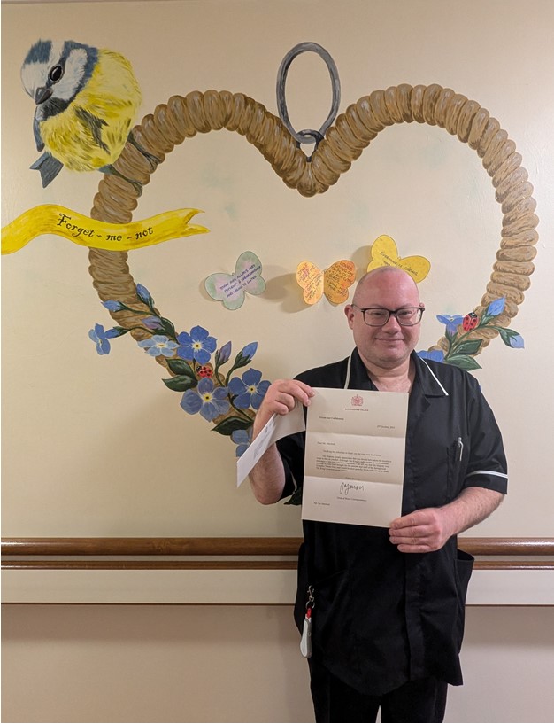 Ian Marshall holding the letter from Buckingham Palace.